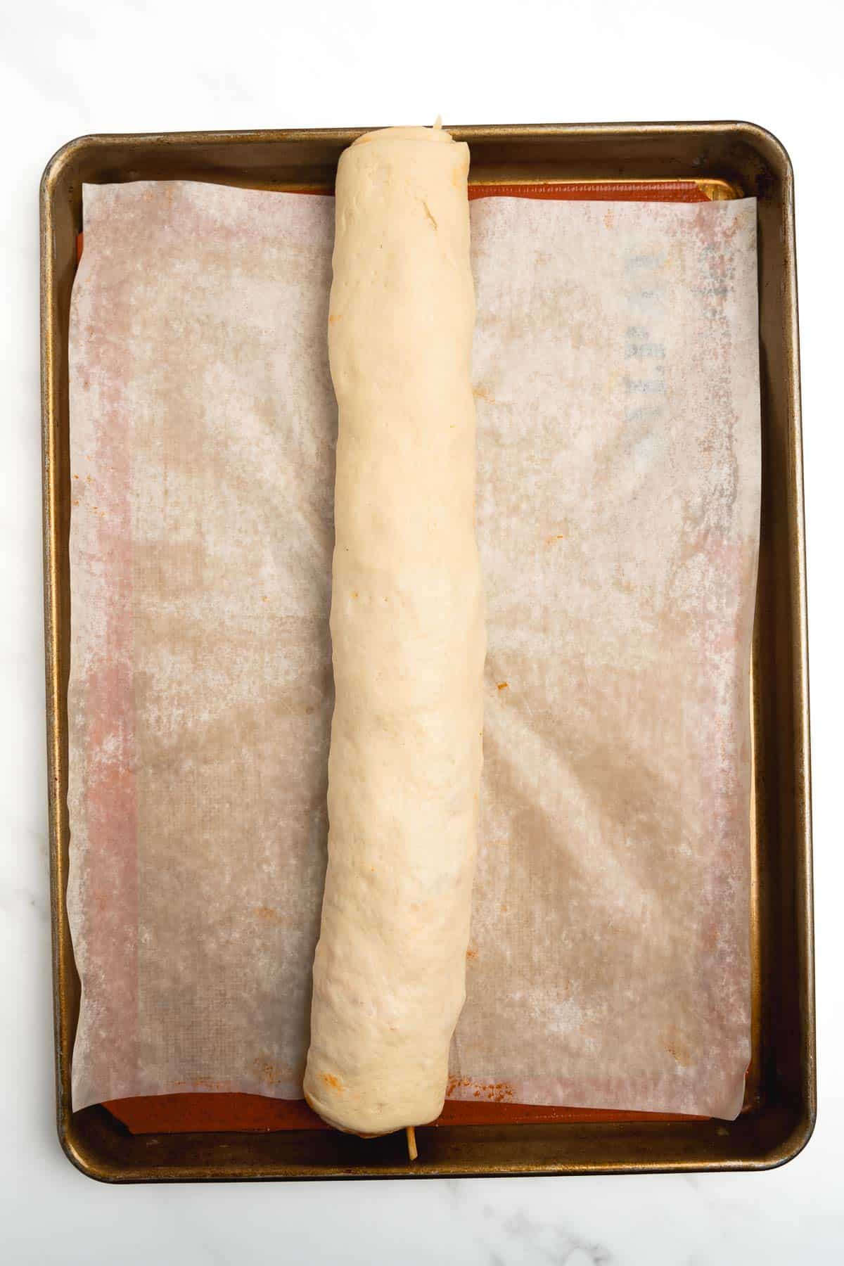 log of pizza dough on a baking sheet.