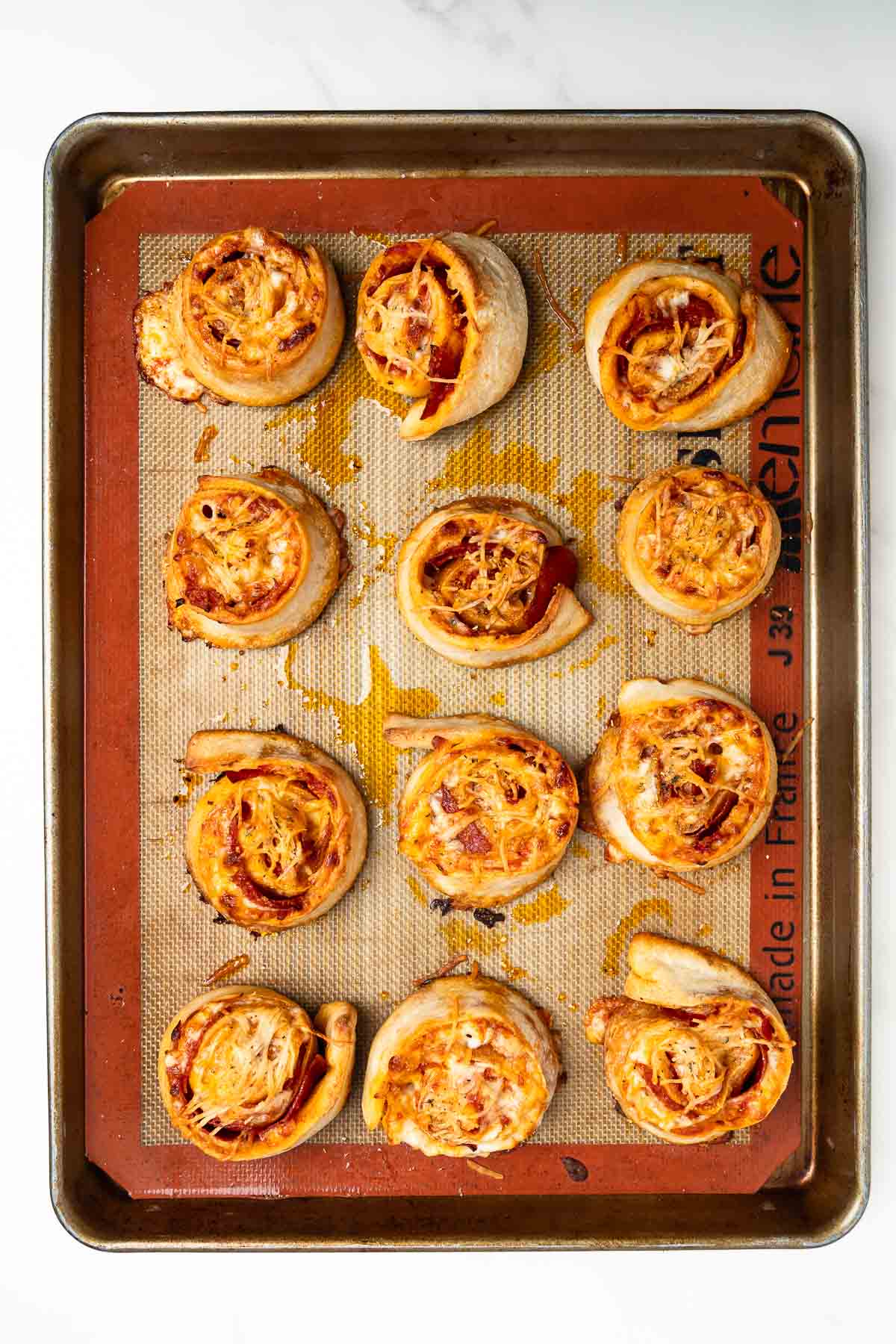 twelve pizza rolls on a baking sheet.