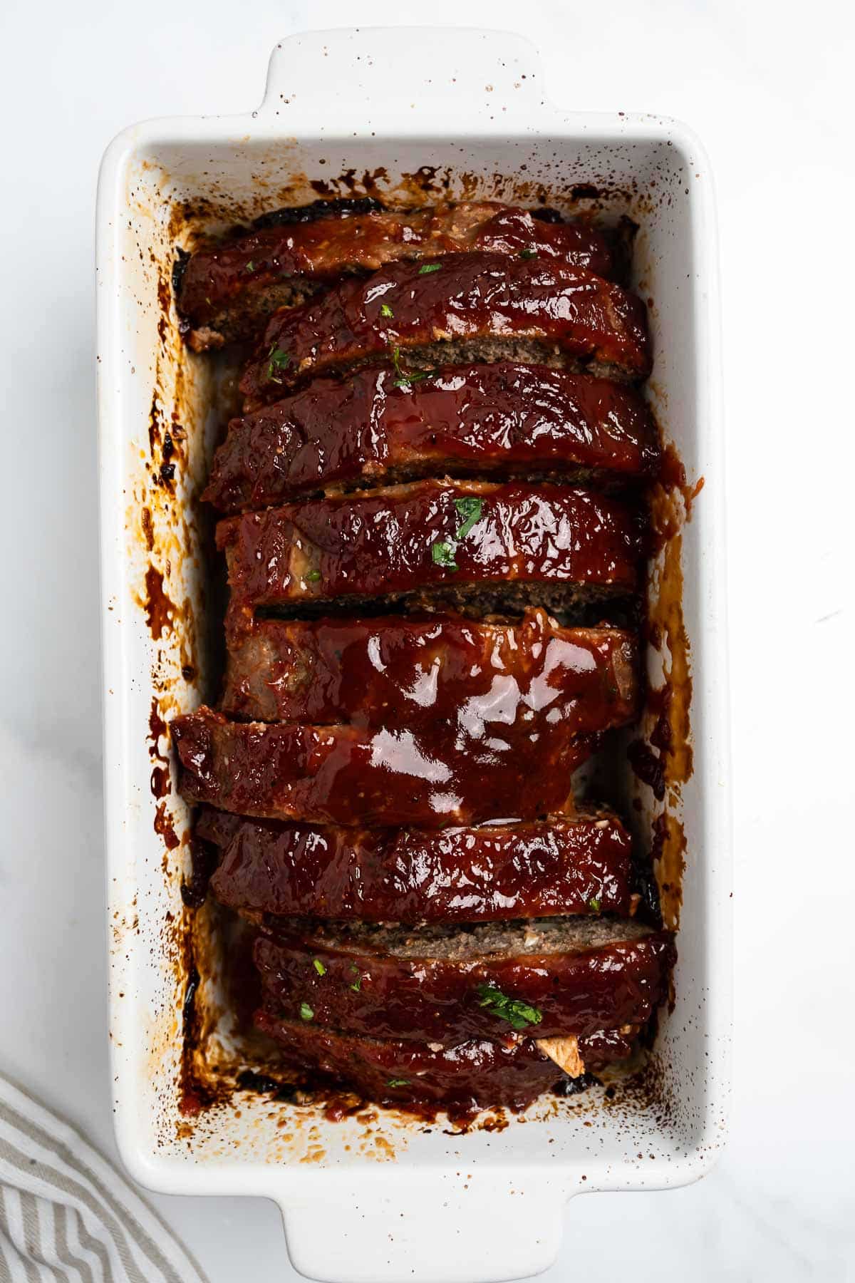 sliced meatloaf in a white loaf pan.