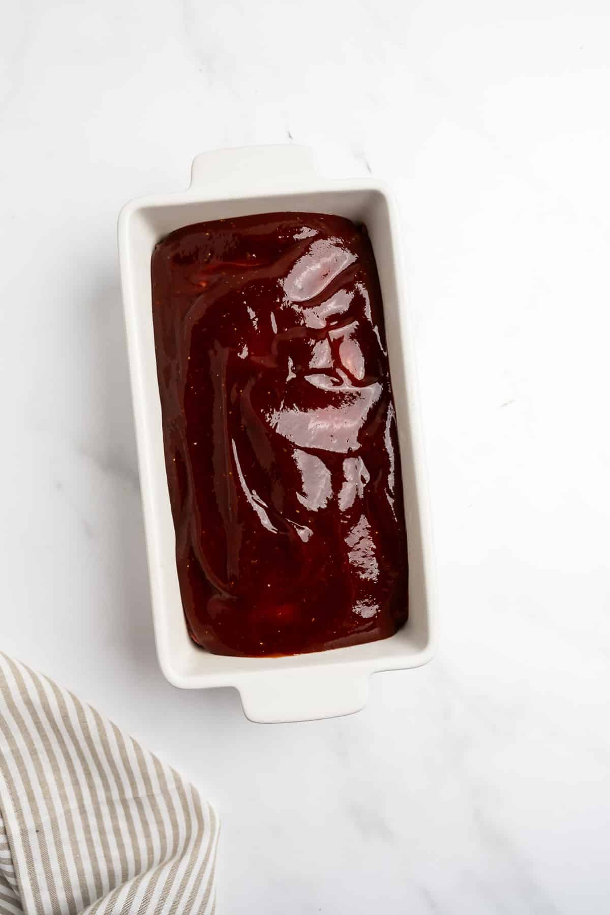 meatloaf in a baking dish with glaze spread on top.