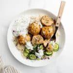 Greek chicken meatballs in a bowl with rice and cucumber.