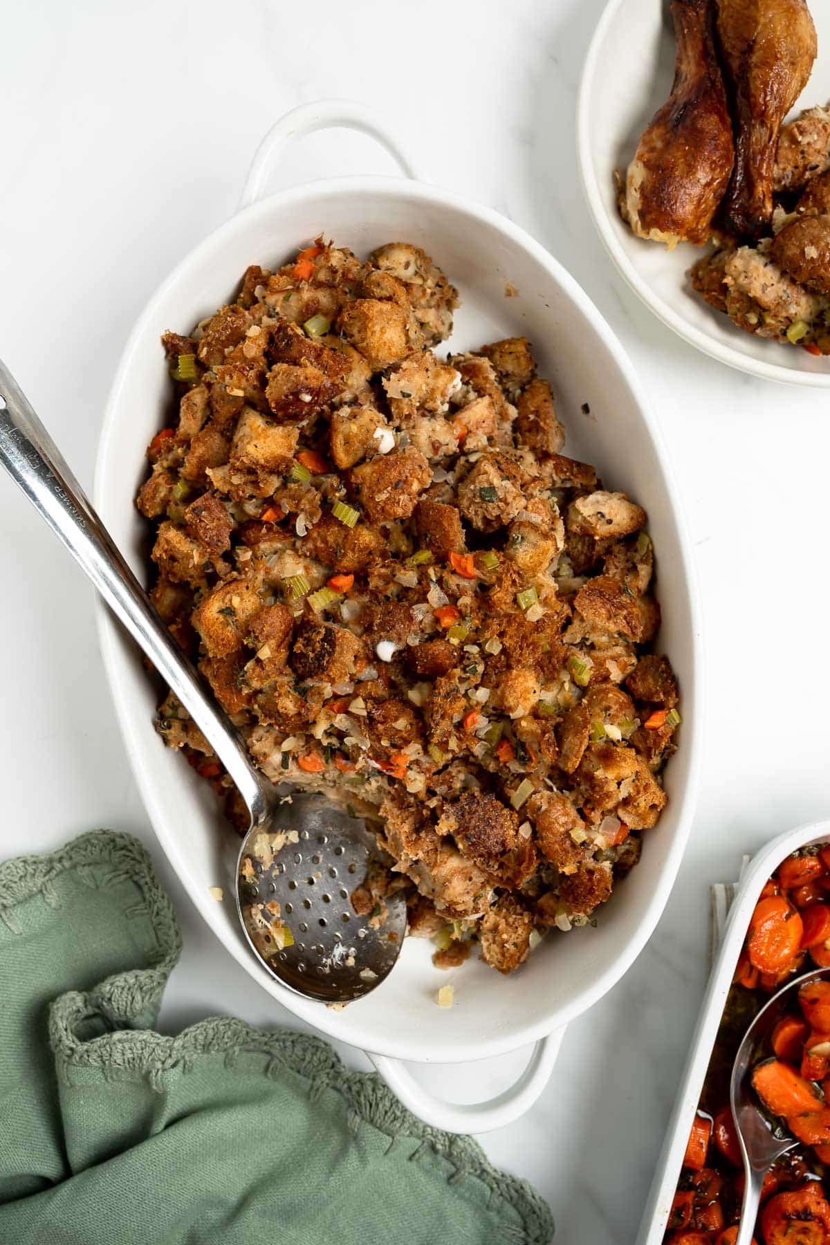 homemade stuffing in an oval baking dish with a serving spoon.