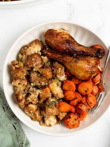 homemade stuffing with turkey legs and carrots on a plate.