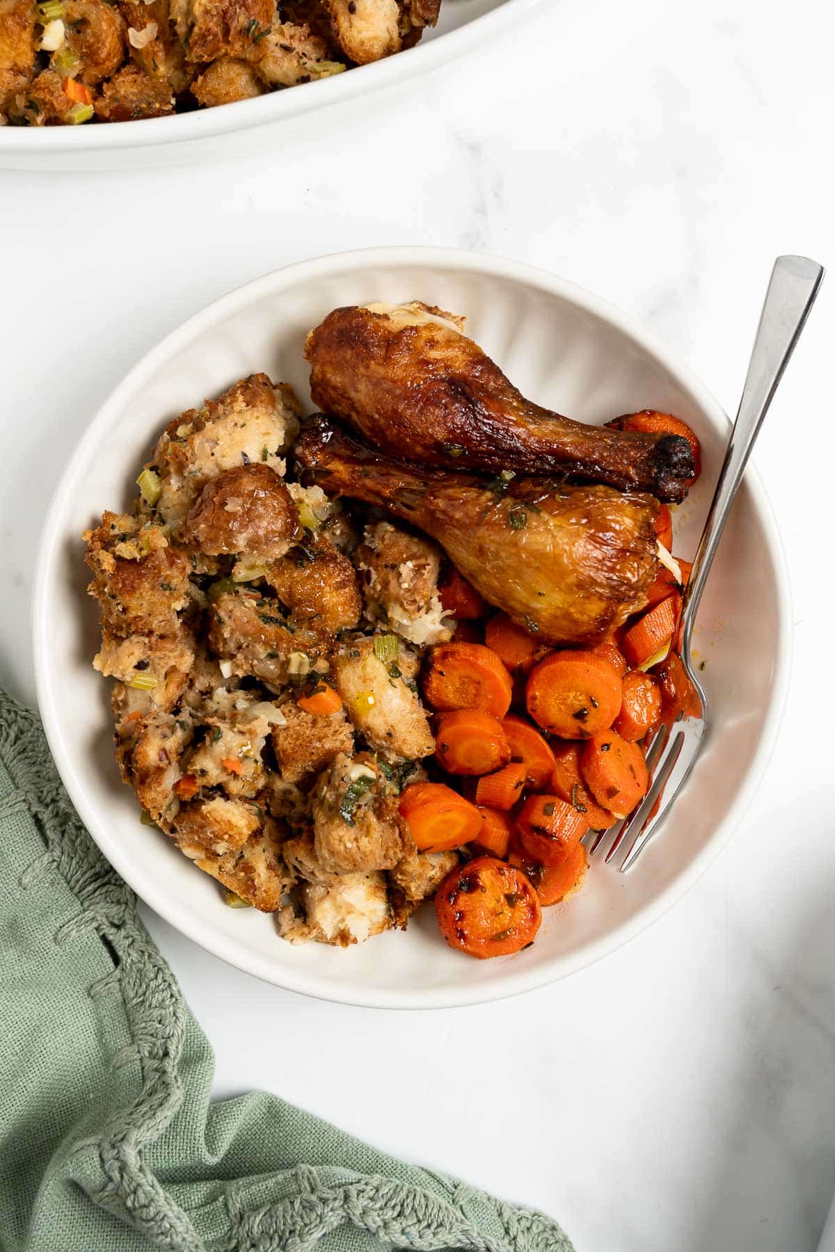 homemade stuffing with turkey legs and glazed carrots on a plate.