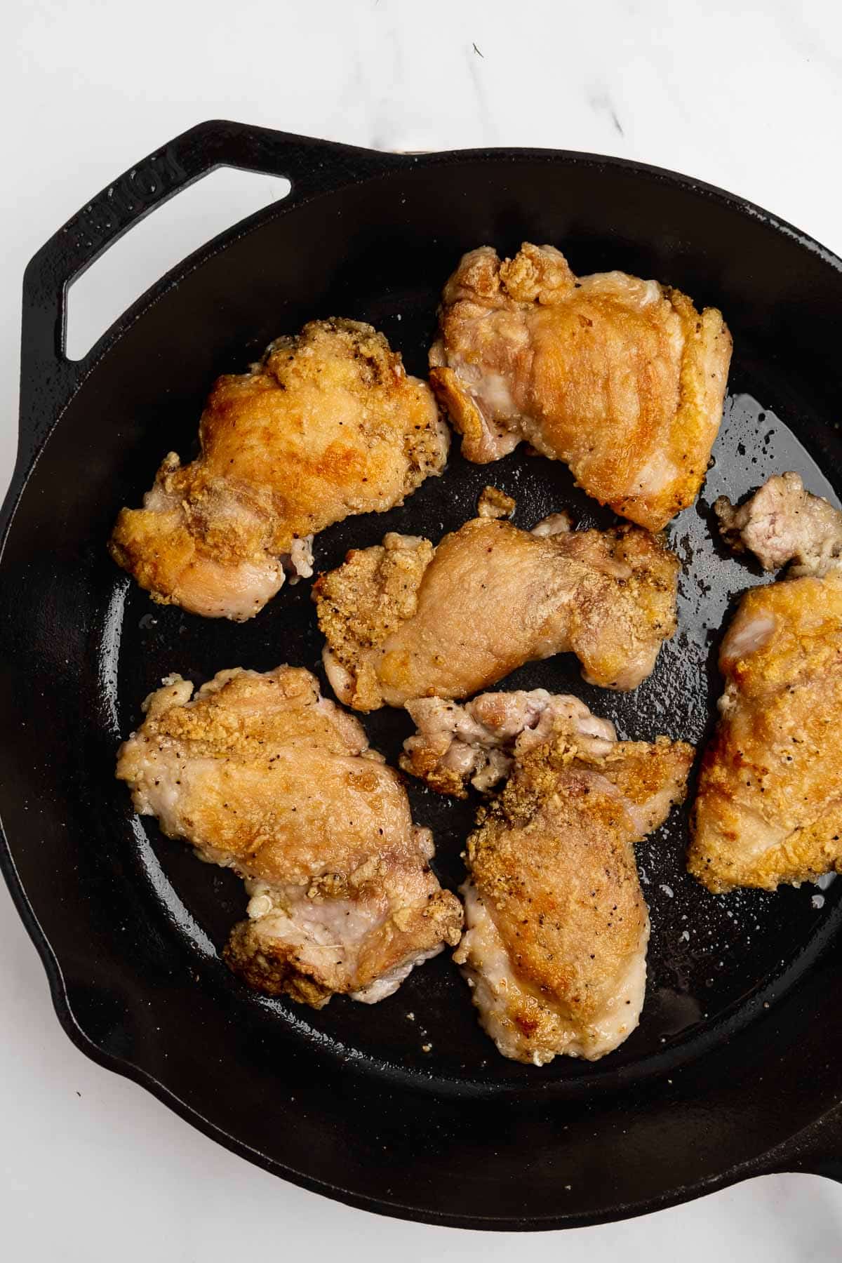 browned chicken thighs in a cast iron skillet.