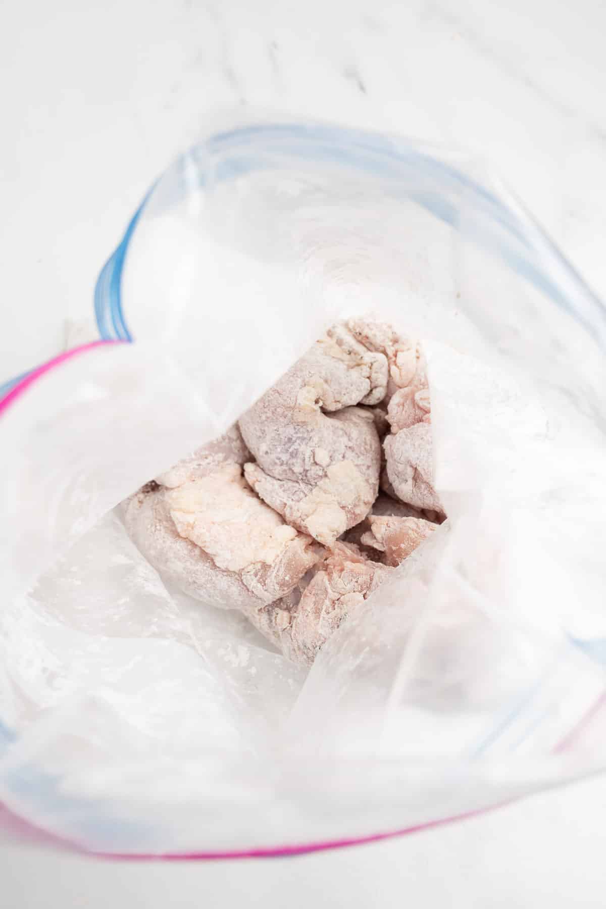 chicken thighs in a zip-top bag coated in spices and cornstarch.