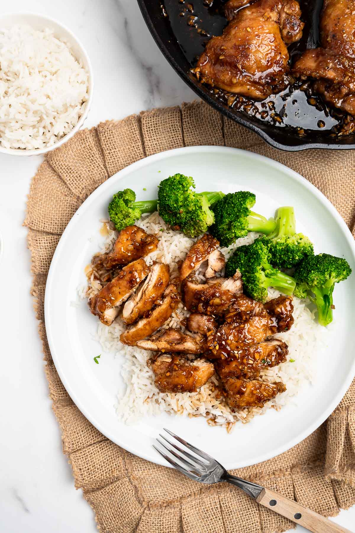 sliced honey garlic chicken thighs over rice with broccoli.