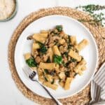 creamy Italian sausage pasta on a white plate with a fork.