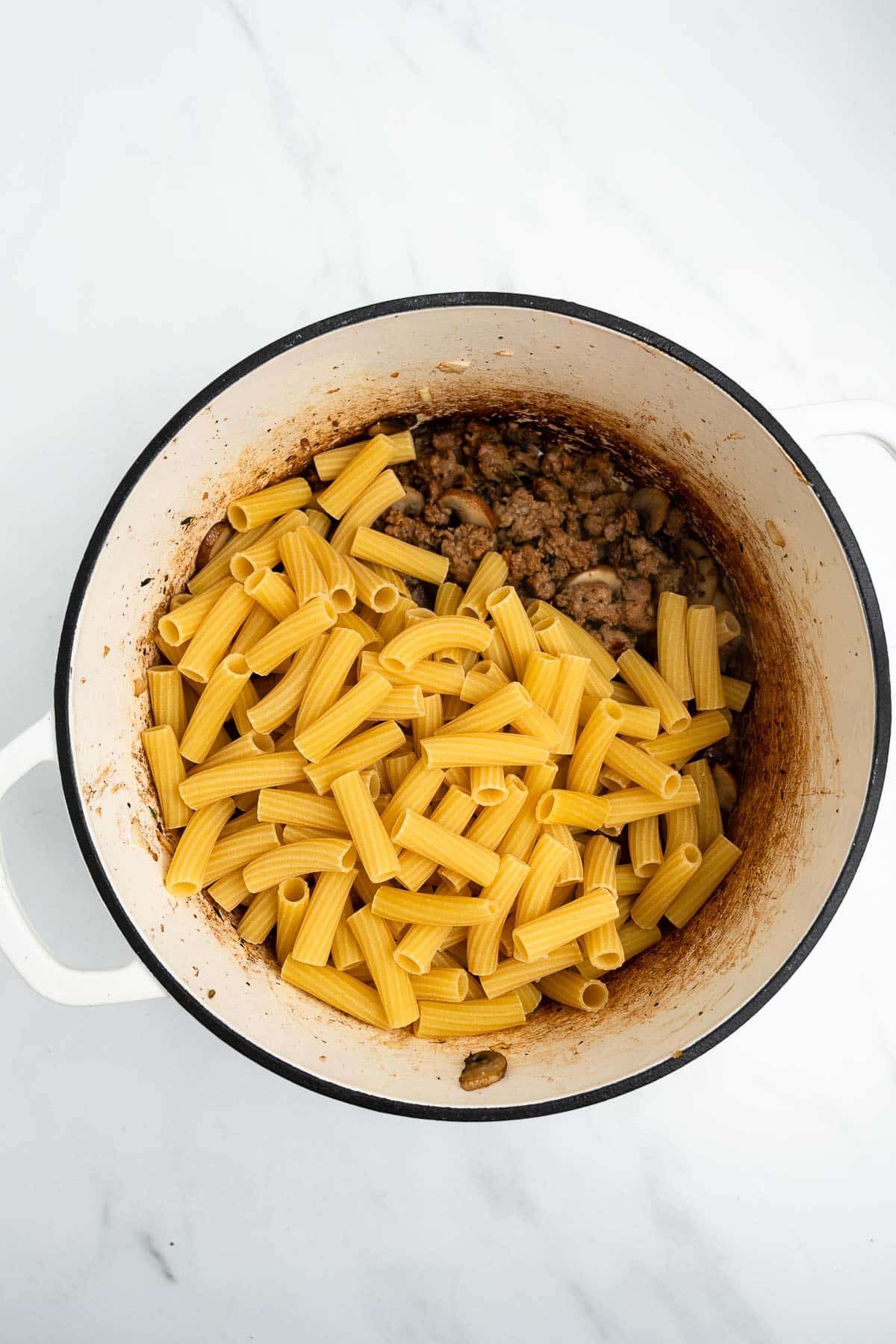ground sausage and rigatoni in a pot.