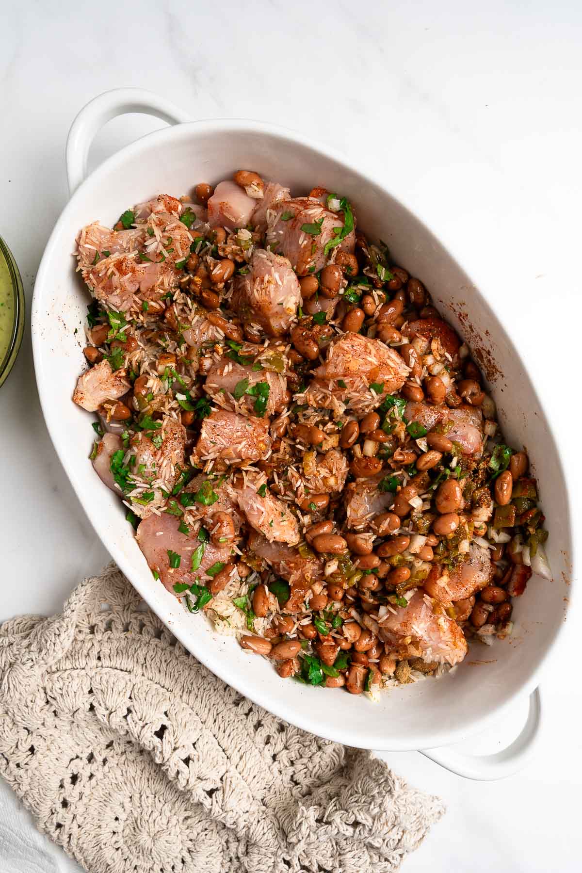 chicken, rice, cilantro, beans, and spices in a baking dish.