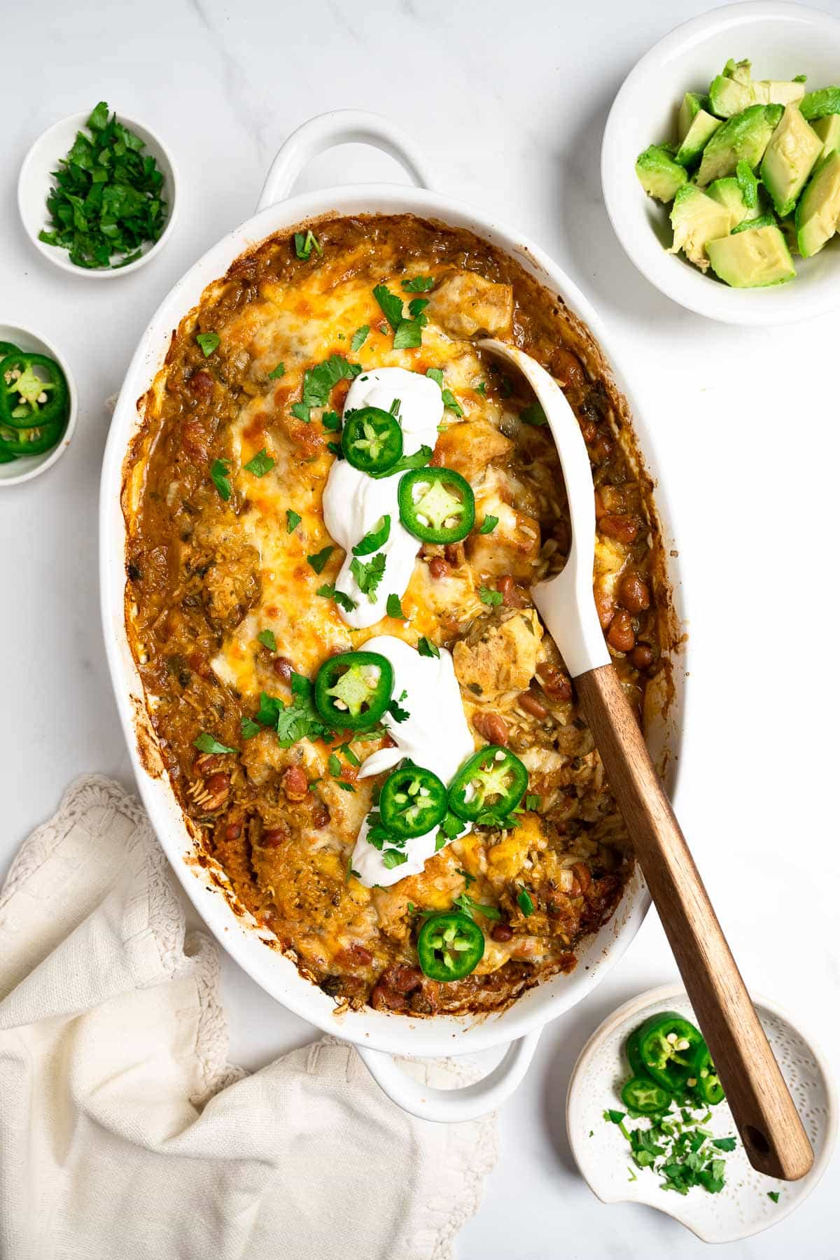 salsa verde chicken and rice in a baking dish topped with sour cream and cilantro.