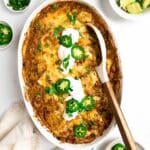 salsa verde chicken and rice in a baking dish topped with sour cream, jalapeños and cilantro.